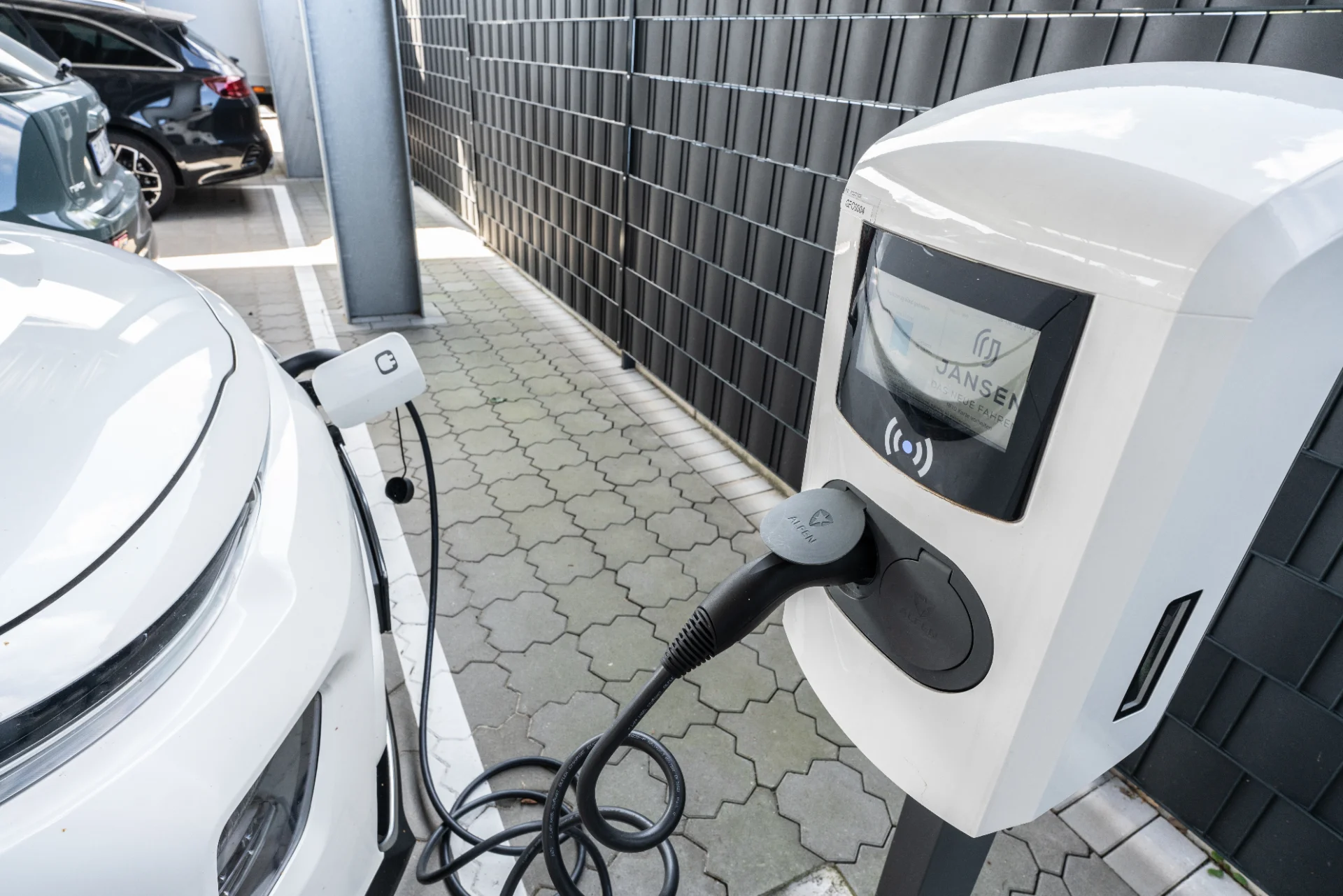 Elektrische auto bij een Jansen-laadstation met aangesloten laadkabel